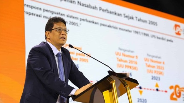Purbaya Yudhi Sadewa, seorang pria berkacamata mengenakan jas biru dan dasi merah, berbicara di depan mikrofon dengan tangan kanannya membuat gestur penjelasan. Di latar belakang terdapat tulisan "Jakarta, 27 Mei 2025" dan logo LPS.